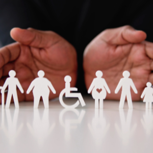 Hands holding paper cutouts of people of diverse sizes  and shapes