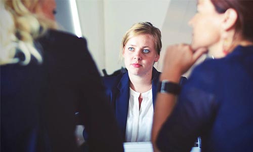 three people in business attire are talking 