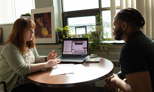 Woman and student chatting at a table in an office