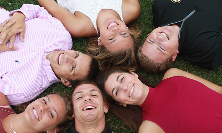 faces of students laying on the ground together